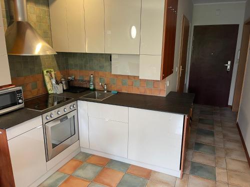 eine Küche mit weißen Schränken und einem Herd mit Backofen in der Unterkunft Apartament w Zielonym Domu in Jurata