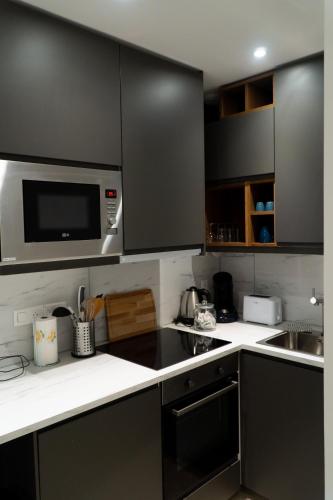 une cuisine avec des armoires noires et un four micro-ondes dans l'établissement L'indiscrete Loveroom, à Saint-Cyr-sur-Loire