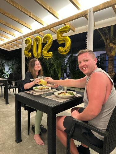 a man and a woman sitting at a table with food at Boli Villa Thoddoo in Thoddoo
