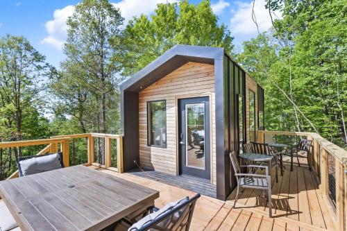 a tiny house with a deck with a table and chairs at The Atlas Cedar Treehouse at Treetop Escapes in Wildwood