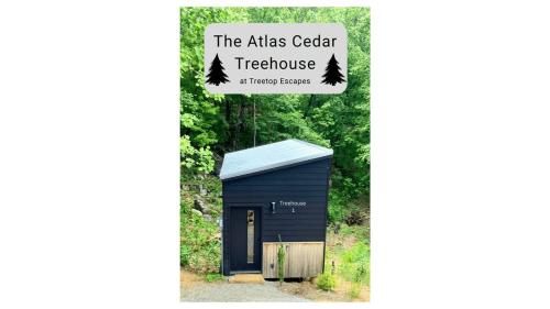 a black shed with trees on the side of it at The Atlas Cedar Treehouse at Treetop Escapes in Wildwood