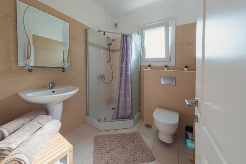 ein Badezimmer mit Waschbecken, Dusche und Toilette in der Unterkunft Roda Luxury Beach House in Roda