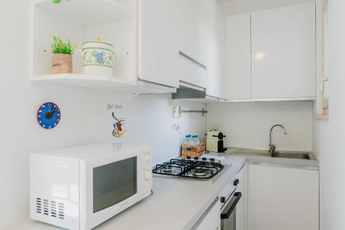 a white kitchen with a stove and a microwave at Forte 25 in Forte dei Marmi