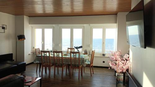 una sala da pranzo con tavolo e sedie e l'oceano di Appartement sur la digue avec vue mer exceptionnelle ! a Bray-Dunes