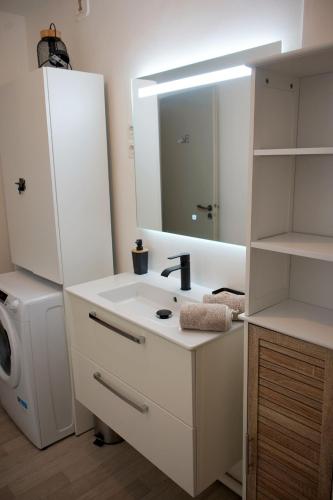 une salle de bain blanche avec un lavabo et un miroir dans l'établissement L'instant Secret, à Saint-Pierre-du-Mont