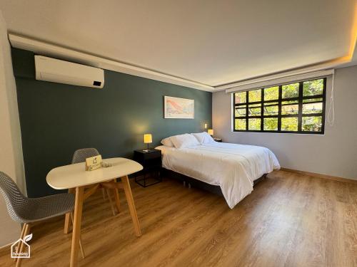 Un dormitorio con una cama y una mesa y una ventana. en Ecohousing, en Medellín