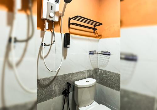 two pictures of a bathroom with a toilet and a shower at Hotel EC Inn in Sepang