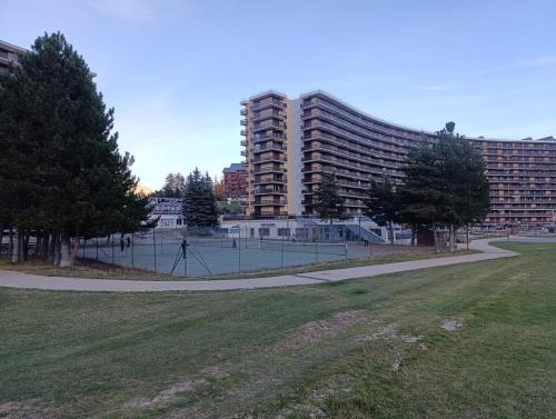 - un court de tennis dans un parc en face d'un bâtiment dans l'établissement Appartement avec vue aux pieds des pistes, à Saint-Étienne-en-Dévoluy