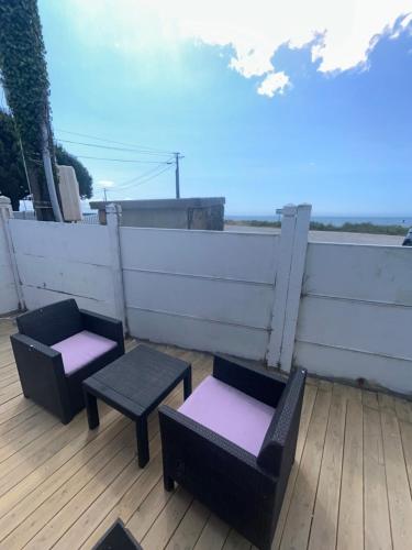 deux chaises et tables sur une terrasse avec une clôture dans l'établissement Petite maison face océan, à Le Tour-du-Parc