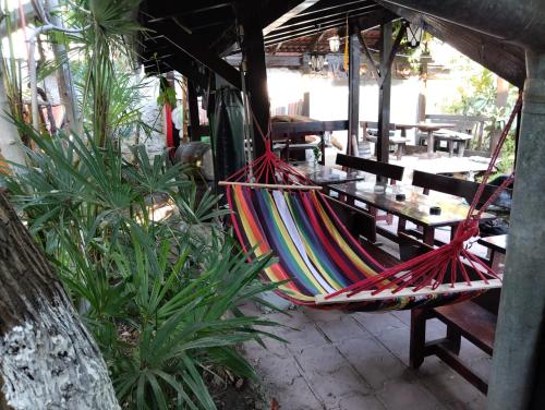 a hammock hanging from a porch with tables and chairs at Hostel Varna Botanika in Varna City