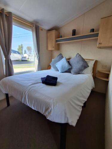 a bedroom with a large white bed with a window at Wonderful 6 Berth Caravan In Norfolk At Heacham Beach, Ref 21012E in Heacham
