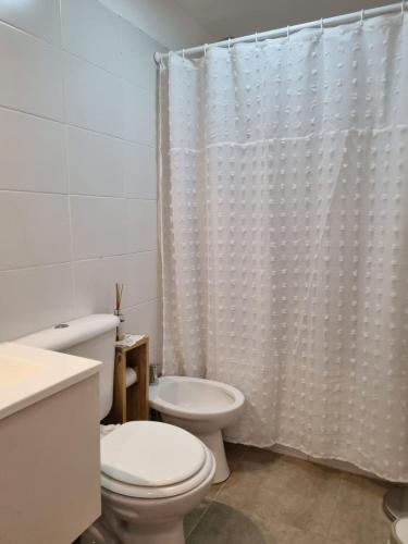 a bathroom with a toilet and a shower curtain at La Nona Nidia in Paraná