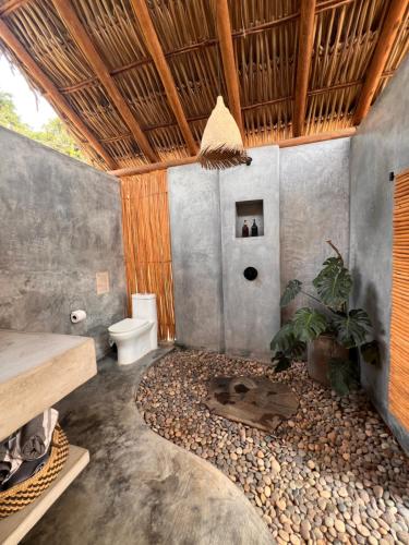 a bathroom with a toilet and a pile of rocks at Casa Copal Troncones - Bungalows con Alberca Privada in Troncones