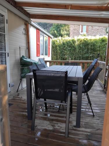 a patio with a table and chairs on a deck at Mobil home LE COUCOU in Le Martinet