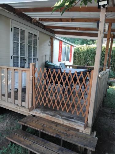 a wooden deck with a gate and a house at Mobil home LE COUCOU in Le Martinet