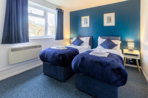 twee bedden in een kamer met blauwe muren bij Cambridge House near Addenbrookes, parking and WiFi! in Shelford