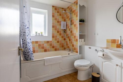 a bathroom with a tub and a toilet and a sink at Cambridge House near Addenbrookes, parking and WiFi in Shelford