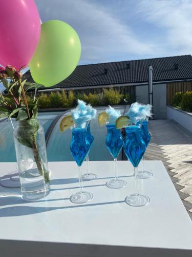 a group of four wine glasses with balloons and a vase at Stan- och strandnära poolvilla. in Halmstad