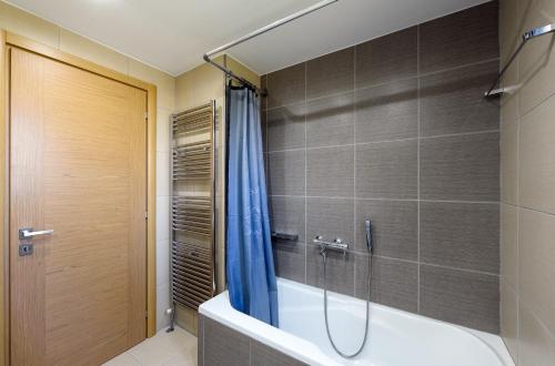 a bathroom with a tub and a shower with a blue shower curtain at Pentanemi Luxury Villa in Hanioti