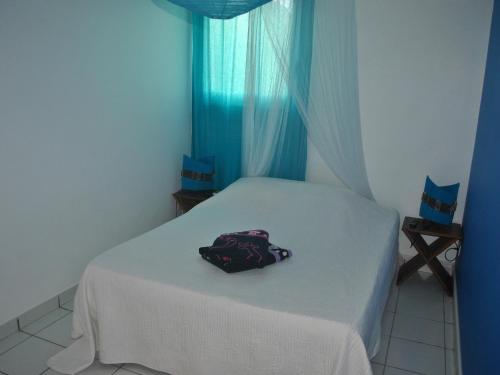 a bedroom with a white bed with a blue window at CoCoKreyol - " ARUBA" in Les Trois-Îlets