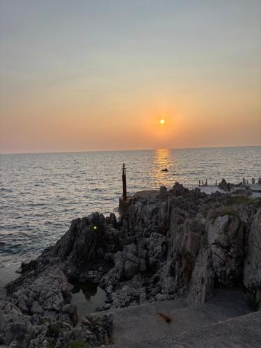 a sunset over the ocean on a rocky beach at Apartments and Studios Anicic in Utjeha