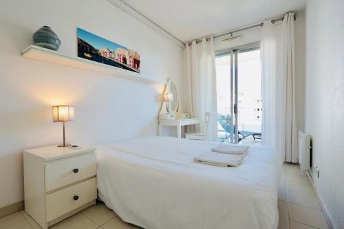 - une chambre blanche avec un lit et une table avec une lampe dans l'établissement Antibes Les Pins - Apt 4 Per - Parc Exflora - Pool, à Antibes