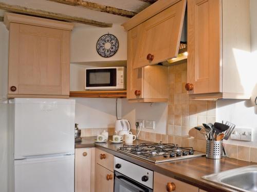 a kitchen with wooden cabinets and a white stove top oven at Church Lane in Llanidloes