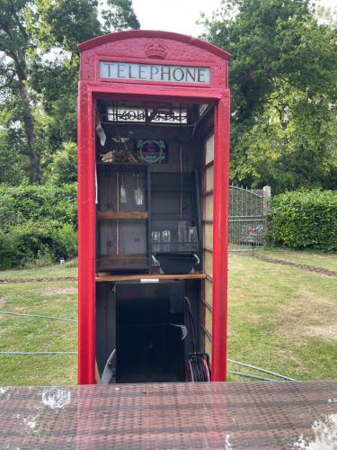 a red phone booth sitting in the grass at South Lodge House in Dormans Land