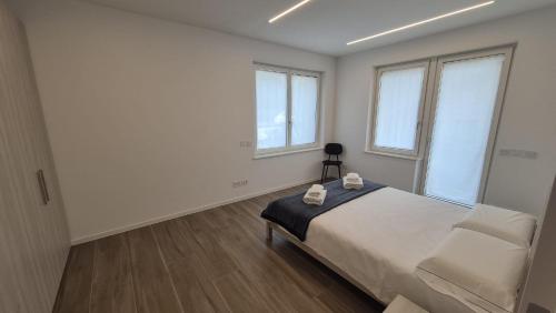 a bedroom with a bed and a chair and windows at Alps lodge in Domegge di Cadore