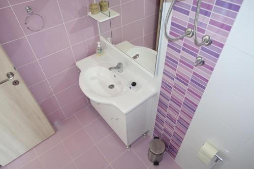 a pink bathroom with a sink and a mirror at Olive Apartments in Ugljan