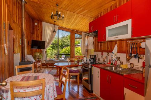 a kitchen and living room with red cabinets at Cabañas Entre Verdes in Frutillar