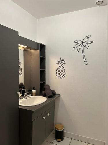 une salle de bain avec un lavabo et des autocollants d'ananas sur le mur dans l'établissement L'Oasis - Halles Châtellerault, à Châtellerault