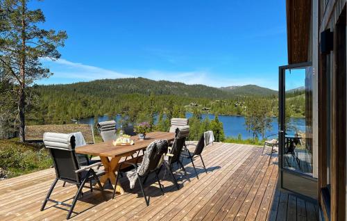 a wooden table and chairs on a deck with a view of a lake at 4 Bedroom Nice Home In Vinje in Trovatn