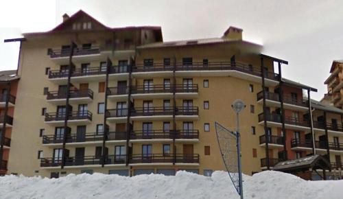 un grand bâtiment avec de la neige devant lui dans l'établissement Appartement Puy Saint Vincent 1700, à Puy-Saint-Vincent