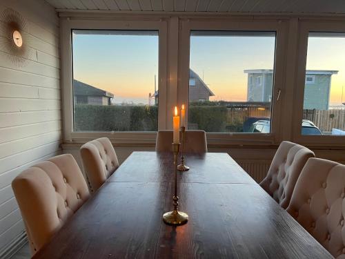a candle on a wooden table in a room with windows at Kleines Paradies an der Nordsee am Großen Meer in Südbrookmerland