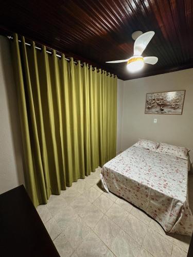 een slaapkamer met groene gordijnen en een bed en een plafond bij cantinho da padroeira in Aparecida