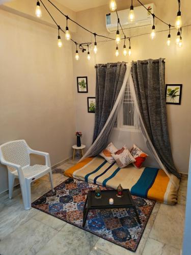a bedroom with a bed and a table and a chair at Hidden Gem - Fully Furnished 1BHK with Café Lights & Canopy, AC & Fast Wifi in Hyderabad