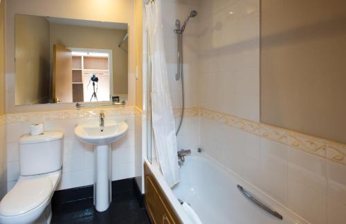 a bathroom with a toilet and a sink and a tub at Mercure Newbury West Grange Hotel in Thatcham