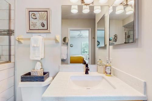 a white bathroom with a sink and a mirror at After Dune Delight in New Smyrna Beach