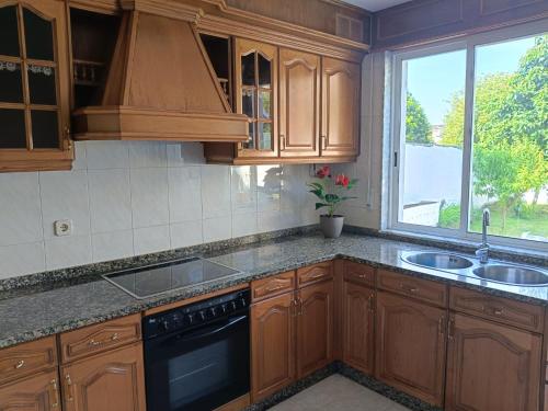 a kitchen with wooden cabinets and a sink and a window at Casa Mugardos in Mugardos