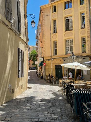 Une rue vide avec des tables et des parasols dans une ville dans l'établissement Duplex calme avec clim, idéal pour flâner à Aix, à Aix-en-Provence
