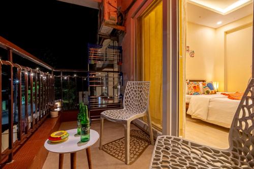 a balcony with a chair and a table and a bed at Siolim by nidra stays in Siolim