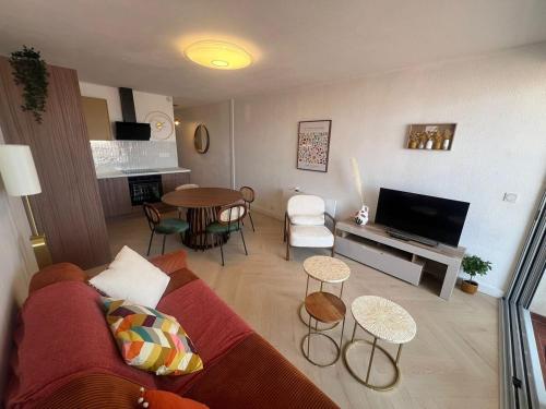 a living room with a red couch and a table at Beautiful apartment with sea view in Le Grau-du-Roi