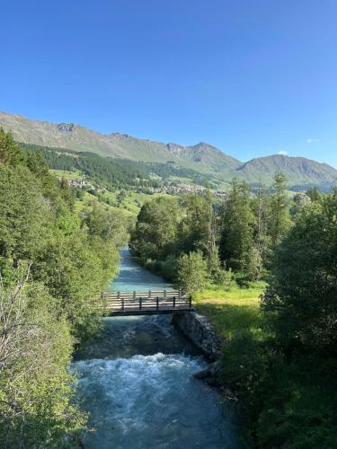a bridge over a river with trees and mountains at Maison Du Coeur Champoluc - Spa, Gym e aree relax in Champoluc