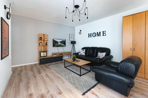 a living room with a black leather couch and a table at Industrial Home Vršac in Vršac