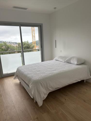 une chambre blanche avec un lit et une grande fenêtre dans l'établissement House with pool, à Vallauris