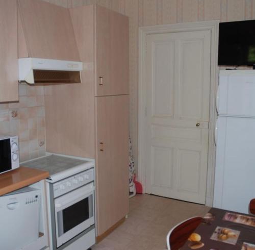 Il comprend une cuisine équipée d'appareils électroménagers blancs et d'un réfrigérateur blanc. dans l'établissement Appartement plein cœur la Bourboule, à La Bourboule