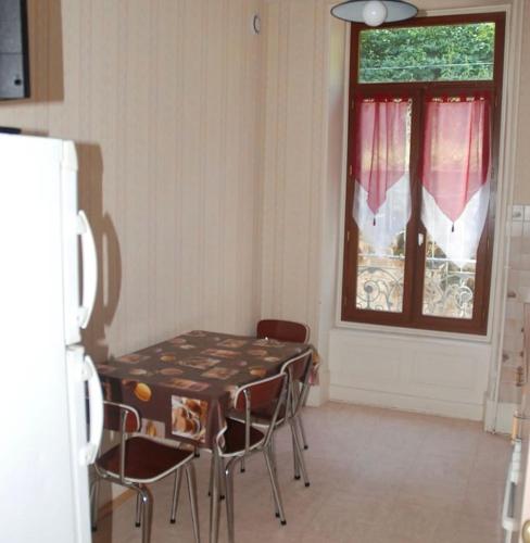une cuisine avec une table et des chaises et une fenêtre dans l'établissement Appartement plein cœur la Bourboule, à La Bourboule