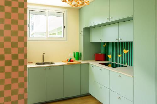 une cuisine avec des placards verts et une fenêtre dans l'établissement L'Addict - 2 Chambres - Clim - Wifi, à Cassis