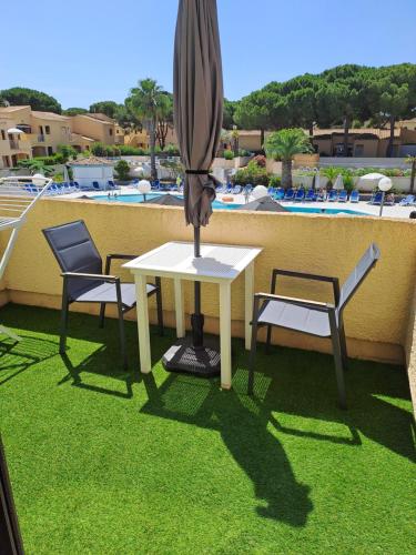 d'une table, de deux chaises et d'un parasol sur le balcon. dans l'établissement Studio Climatisé Résidence Odalys nouvelle box 5 G ,Saint Loup,piscine ,parking privé et superette, au Cap d'Agde